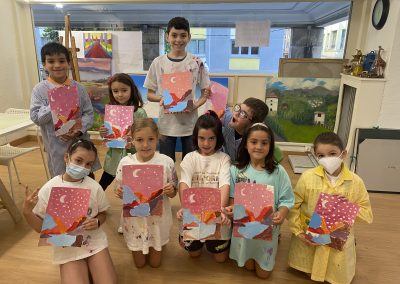 Grupo de niños con sus cuadros en clase de dibujo y pintura
