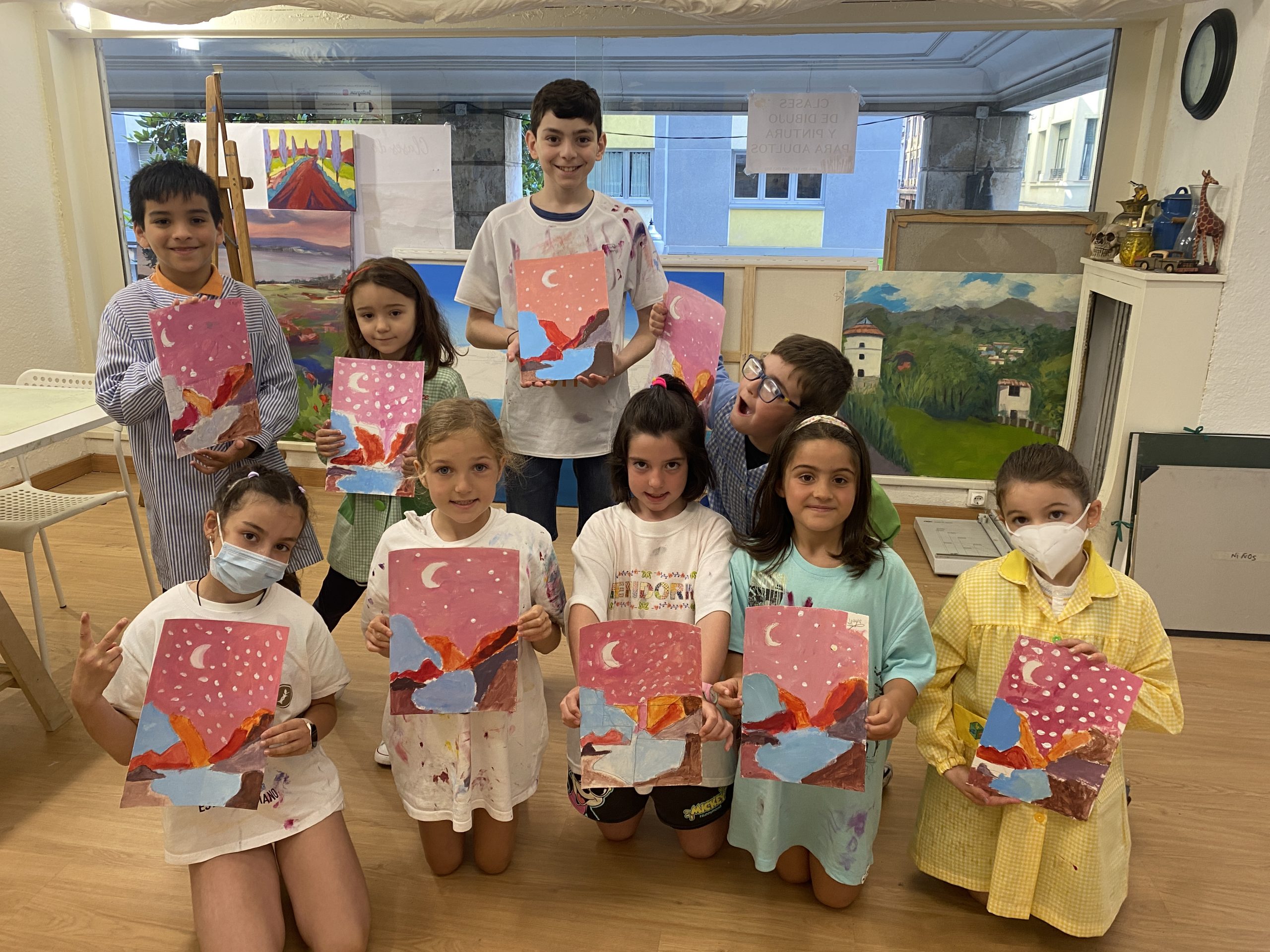 Grupo de niños con sus cuadros en clase de dibujo y pintura